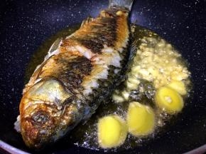 将鱼煎至两面金黄，将生姜蒜放入爆香