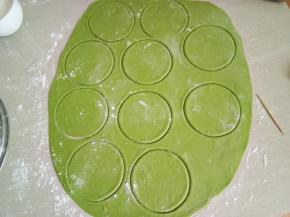 发好的绿色面团充分按揉排气，擀成薄面片用圆形模具压出圆面片。