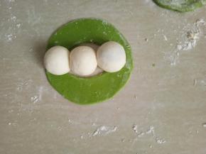 把面皮展开，摆上揉圆的三个小白面团。