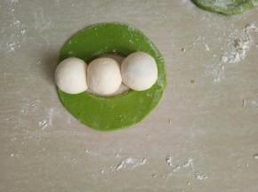 把面皮展开，摆上揉圆的三个小白面团。