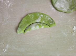 取一片面皮对折，压出月牙状，把压出的部分去掉。