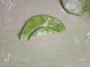 取一片面皮对折，压出月牙状，把压出的部分去掉。