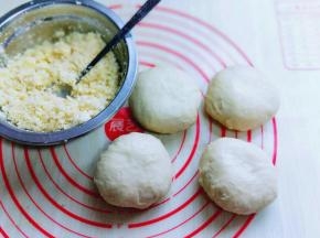 制作椰蓉馅。椰蓉中加入蛋黄，白砂糖，黄油。用勺子搅拌均匀即可。
发酵好的面团取出排气。并分割成4等份。