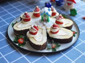 蛋糕卷切片后摆入盘中，草莓挤上奶油装扮成圣诞老人后摆入，最后撒上少许防潮糖粉，完成。