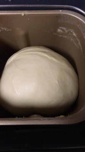 然后将发酵好的面团与主面团中除黄油外所有的材料放入面团机中（注意放入顺序，先液体再粉状物），开启搅拌机的揉面功能，将面团搅拌成光滑状，然后再加入室温软化的黄油，搅拌至扩展阶段。