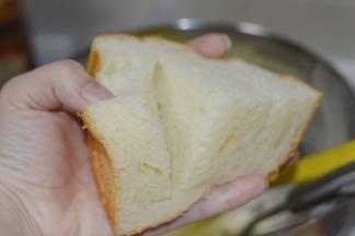 放凉的面包用面包刀平分为四份，再在面包上割上两刀，把奶酪馅填入其中，表面也可以稍微涂抹一些。