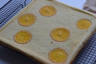 烤好的蛋糕卷轻震几下，然后倒放到烤网上晾凉，趁热揭去油布。