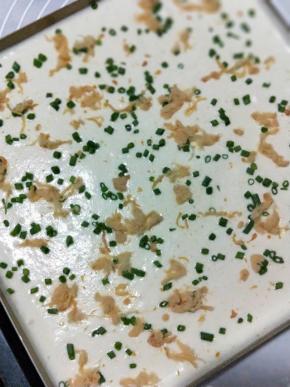 拌好的蛋糕糊倒入铺了油纸或烤垫的金盘内，利用刮刀把表面刮平整，撒上葱花与肉松
