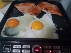 鸡排移到边缘，然后淋少许油，打入鸡蛋，喜欢造型的可以放2个煎蛋器