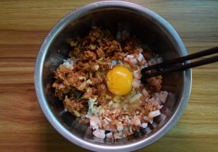 把辣白菜、虾、鱿鱼和煎出油的肉末一起放盘里，加入姜末，打入一个鸡蛋