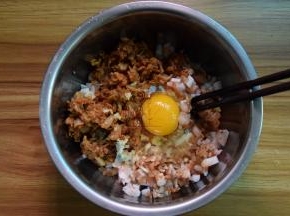 把辣白菜、虾、鱿鱼和煎出油的肉末一起放盘里，加入姜末，打入一个鸡蛋