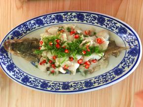 在鱼身上铺上葱花丝和小米椒。