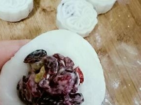 面团压扁，皮上放馅，包包子似的收口，团圆，放在放了熟糯米粉的案板上。