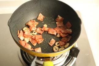 炒锅放少许底油润锅，培根和蒜片放入煸炒出香味，培根变焦香。