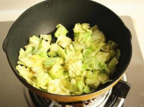 下入甘蓝菜炒软。加一点点盐给甘蓝菜调味。