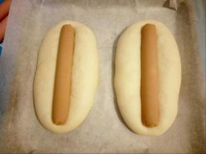 二次发酵完成后，将火腿肠放入面包中间，轻轻往下按