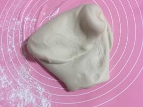 面板上撒少许面粉，发酵好的面团取出来排气，使劲儿揉大约200下左右！（面团揉的越久做出来的包子表面越光滑！）