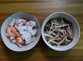 将鱿鱼和虾放沸水焯几秒捞出，蟹味菇去掉根部洗净焯水