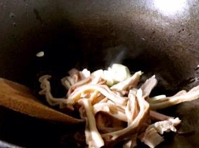 锅烧热油，放入蒜片和猪肚条，一起炒出香味