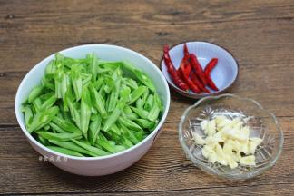 四季豆撕去两边的老筋，洗净，切斜刀段、蒜瓣去皮拍碎、辣椒摘洗净