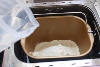 将面粉倒入面包桶内、加上白糖、酵母和温水