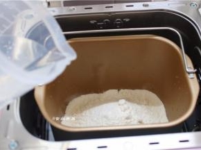 将面粉倒入面包桶内、加上白糖、酵母和温水