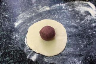 取一个白面团擀成面皮，再把紫薯球放在中间