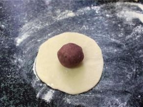 取一个白面团擀成面皮，再把紫薯球放在中间