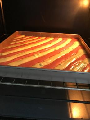 轻震出大气泡，放入预热好180度烤箱中，烤20分钟。
烤好的蛋糕卷立刻取出，拉住油布将蛋糕卷取出，放到晾网上，垫一张油纸，倒扣，将油布撕掉，盖上油纸。