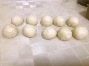 把面团光滑面向下，倒到面板上，用手按压排出气体，然后把面团均匀的分成10份（也可以根据自家烤盘的型号来分），然后光滑面在外，把切面包到里面，揉成光滑的小面团。