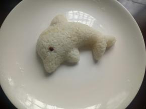 取一个大点的盘子，用磨具把饭倒扣在盘子里，加上眼睛，可爱的海豚饭团就做好了！