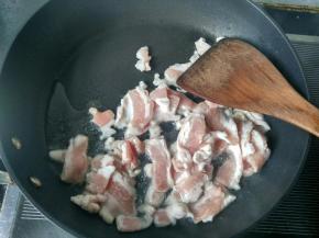 将五花肉倒入锅中翻炒。