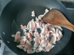 将五花肉倒入锅中翻炒。