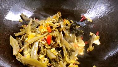 放入酸菜和泡椒碎，煸炒出香味