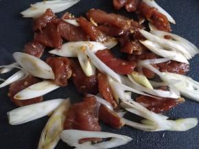 电饼铛里放少许油，然后倒入腌制好的肉片和葱片