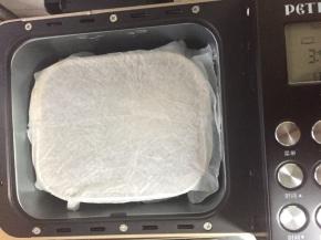 面团放入面包机内（或温暖地方），厨房纸吸湿稍拧干水分（不滴水即可）盖在面包桶上方，盖上面包机盖子进行发酵50分钟