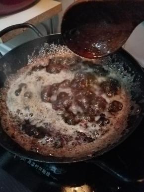 将在一旁熬煮的干贝、海米和火腿倒回油锅中。