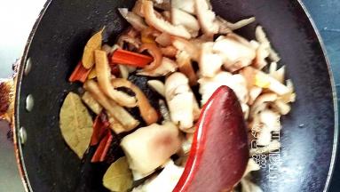 倒入猪蹄和猪皮翻炒，倒入姜蒜翻炒，再倒入香料翻炒出香味，倒入料酒和生抽翻炒