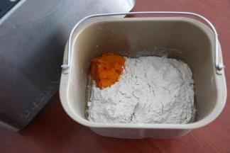 面包机桶内，先加入牛奶、鸡蛋、玉米油，盐、糖对角线放置，再加入高筋粉、南瓜泥，最后在面粉上面挖一个小洞，放入酵母。切记不要让酵母接触到盐。