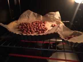 准备一张烘培纸揉搓成团再展开（另烘焙纸更加柔软不易弄破饼皮），烘培纸上撒上花生米也可以撒上派石或者类似的重物颗粒，避免因饼皮温度升高而饼皮拱起，烤箱上下预热180度烤制10-15分钟