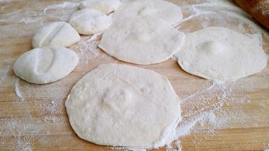 剂子按扁，然后擀成中间略厚，四周薄得包子皮。