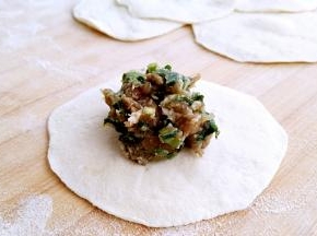 取一张包子皮，中间放入适量肉馅。