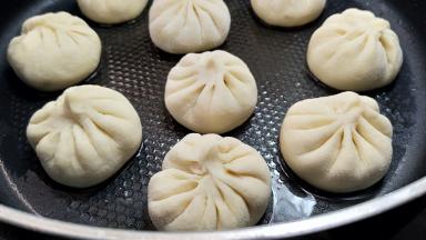 包子醒发到比原先大了很多，开启中小火煎。