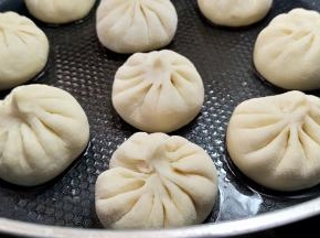 包子醒发到比原先大了很多，开启中小火煎。