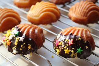 黑巧克力加适量牛奶和白糖，隔热水融化，玛德琳在巧克力酱里滚一下，撒少许橙皮屑和装饰糖，就非常漂亮了，