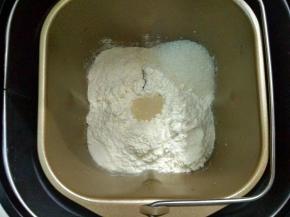 把除黄油的面团材料放入面包桶，糖和盐对角放，中间挖个坑放入酵母，启动面包机揉面。