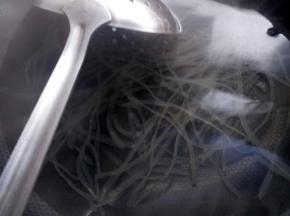 锅中下入薯粉煮软化后捞起，接着下入香菇片烫熟。