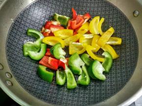 放入青、红、黄椒翻炒至快熟。