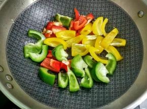 放入青、红、黄椒翻炒至快熟。