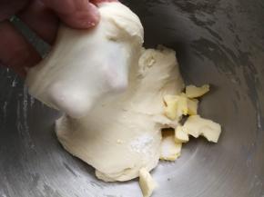 启动厨师机和面，至面团能拉出粗膜，加入软化的黄油和盐